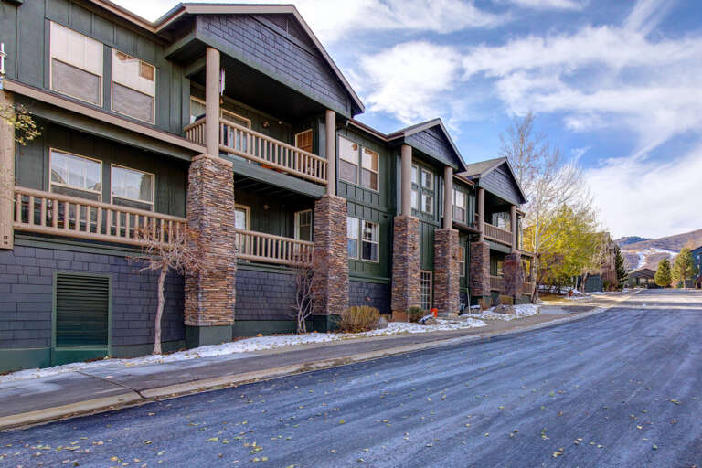 Mountain-side multi-unit property featuring stacked stone accents, private balconies, and alpine architecture in a quiet neighborhood setting near ski slopes.