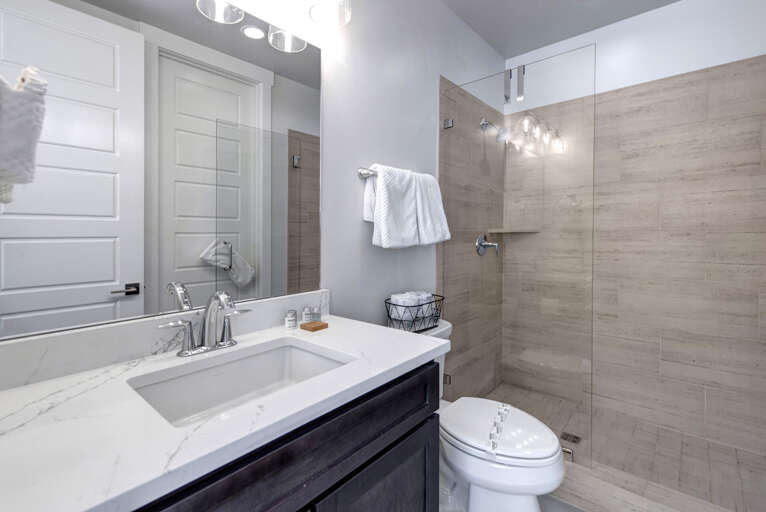 Step into your beautifully refreshed private bathroom, where modern design meets relaxation. Enjoy plush towels, elegant lighting, and a spacious shower with warm wood-tone tile that creates a spa-like retreat.