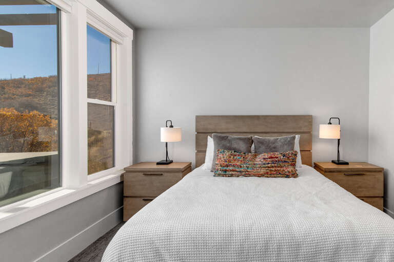 Wake to breathtaking views of golden hills and open skies. Your cozy retreat features a plush bed, warm bedside lighting, and windows framing nature's beauty just for you.