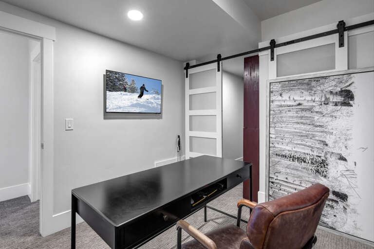 Your own private workspace with a sleek desk, barn door charm, and mountain-inspired art—perfect for catching up on work between adventures.