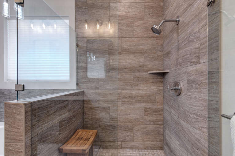 Unwind in this beautifully designed spa-like shower with natural stone tiling and your own warm wooden bench for ultimate relaxation.