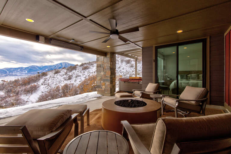 Gather around the modern fire pit on your private terrace, where heated comfort meets sweeping mountain vistas. Stylish seating invites you to unwind with winter's beauty stretching endlessly before you.