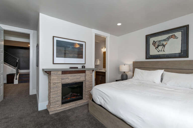 Sink into crisp white linens while the fireplace glows warmly at your bedside. Your private ensuite awaits just steps away, and upstairs access adds extra space to call your own.