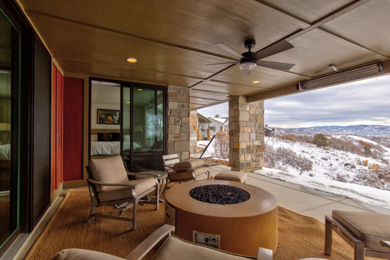 Relax on your private covered terrace with a cozy fire pit, plush seating, and breathtaking winter mountain views stretching to the horizon.