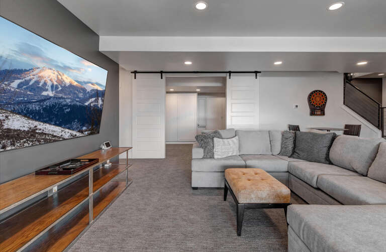 Unwind in your spacious living area featuring a sectional sofa, entertainment system, and modern barn doors. Perfect for cozy evenings after mountain adventures.