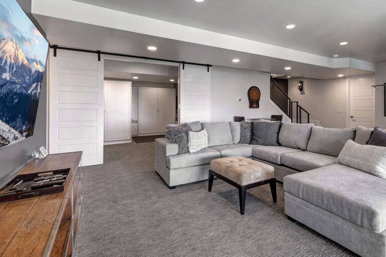 Sink into the plush sectional and enjoy movie nights on the big screen in this cozy, modern lounge with stylish barn doors and ample seating for everyone.