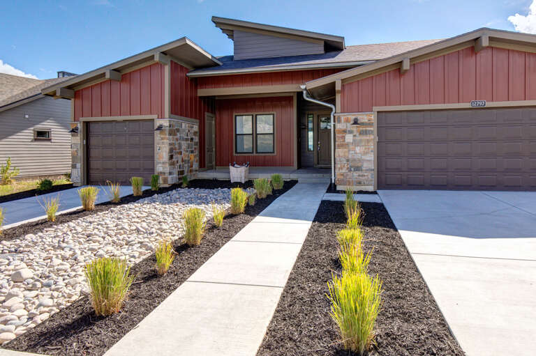 Modern red-paneled exterior with stone accents and drought-resistant landscaping welcomes you to a stylish mountain retreat.