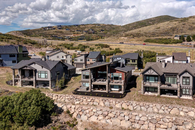 Aerial view showcasing modern vacation rental homes nestled into rolling hillside terrain with natural stone landscaping and mountain vistas beyond.