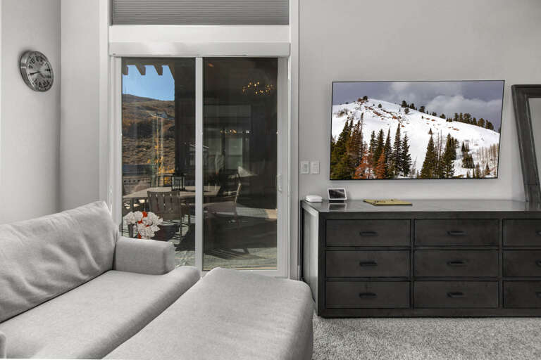 Relax in your cozy living room with plush seating, mountain views from your patio door, and entertainment ready on the flat-screen TV above sleek storage.