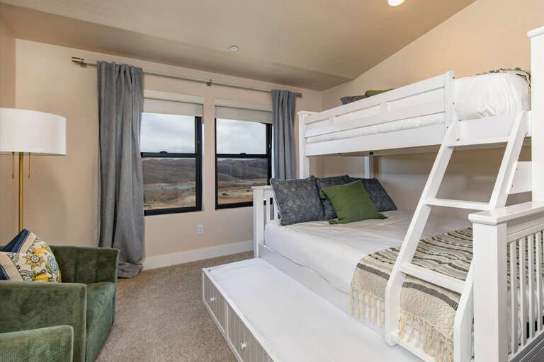 Spacious bedroom with custom bunk beds offering scenic hillside views, perfect for families. Extra seating lets you unwind while enjoying the peaceful landscape outside your windows.