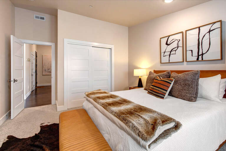 Settle into crisp linens and plush textures after a day exploring. Your modern bedroom features soft lighting, abstract art, and a cozy bench at the foot of your comfortable bed.