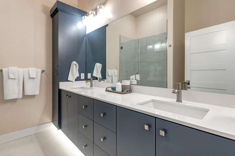 Step into your modern bathroom with dual vanities, sleek quartz countertops, and a spacious walk-in shower—a refreshing retreat after a day of exploring.