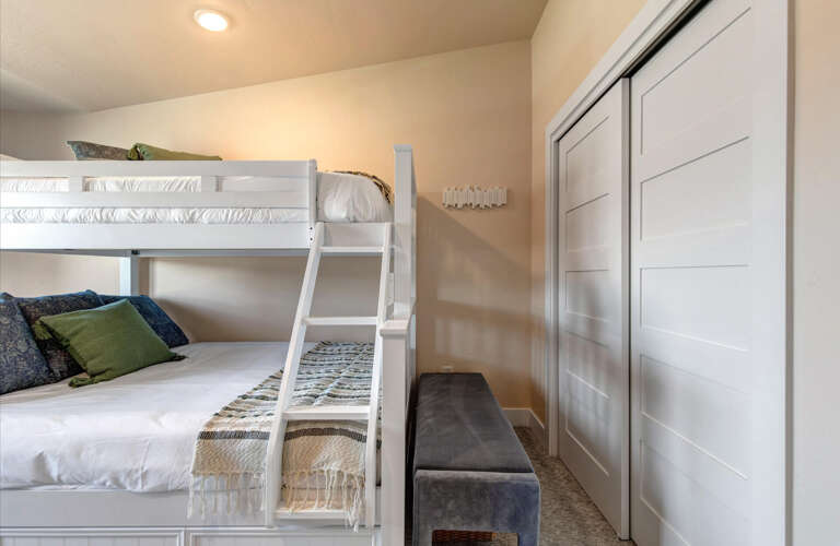 Your cozy bedroom features crisp white bunks with soft linens, perfect for family stays. Store your belongings easily in the built-in closet while relaxing on the plush bench.