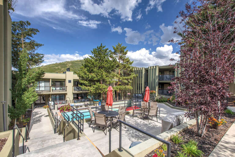 This property sits nestled at the base of a scenic hillside, offering a tranquil setting with mountain views. The multi-building complex features balconies, mature trees, and outdoor gathering spaces, creating a peaceful retreat in the surrounding natural