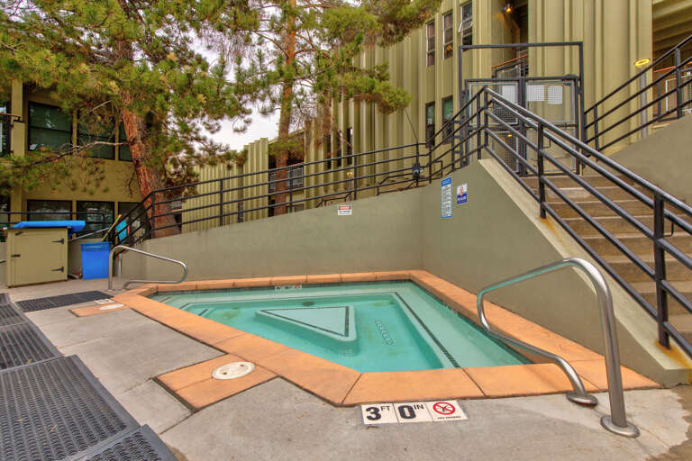A private hot tub awaits just steps from your door, nestled in a quiet courtyard surrounded by tall pines—your perfect spot to unwind under open skies.