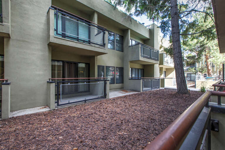 Modern multi-level property nestled among towering pines, featuring private balconies and contemporary architecture in a peaceful natural setting.