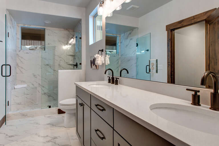 Step into your spa-like bathroom with elegant marble finishes, a walk-in shower, and dual vanities illuminated by warm lighting—your perfect retreat after a day of adventure.