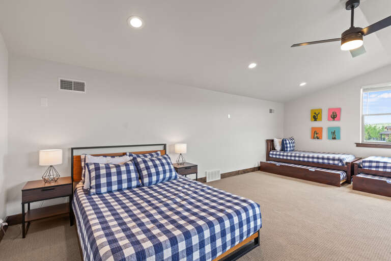 Your spacious retreat features comfortable beds with cheerful accents, modern ceiling fan, and bright natural light streaming through large windows—perfect for restful nights and easy mornings.
