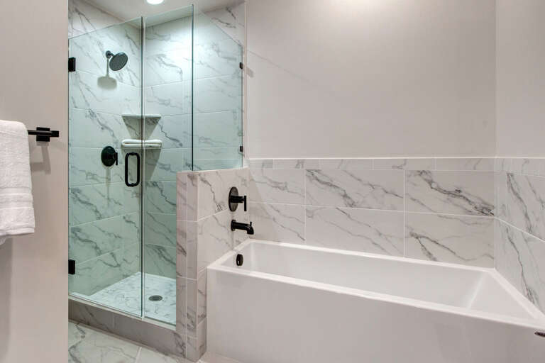 Unwind in your private spa-like bathroom with a sleek glass-enclosed shower and a deep soaking tub, both finished in elegant marble-look tile.