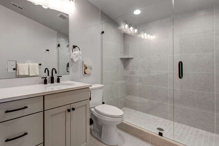 Refresh in your modern bathroom with sleek gray tiling, a spacious walk-in shower, and elegant black fixtures that bring contemporary style to your daily routine.