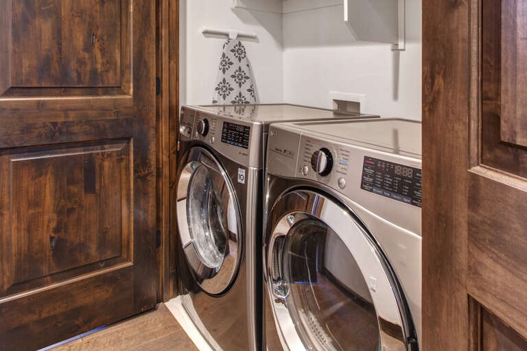 Your vacation laundry is handled in this sleek, private laundry space with a modern front-loading washer and dryer tucked neatly between rich wood cabinetry.