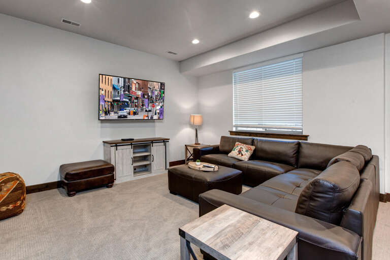 Sink into plush leather seating and enjoy your favorite shows in this inviting lounge area with modern entertainment setup and natural light.