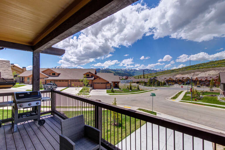Covered balcony showcasing snow-capped mountain vistas and peaceful neighborhood surroundings, framed by a residential hillside setting.