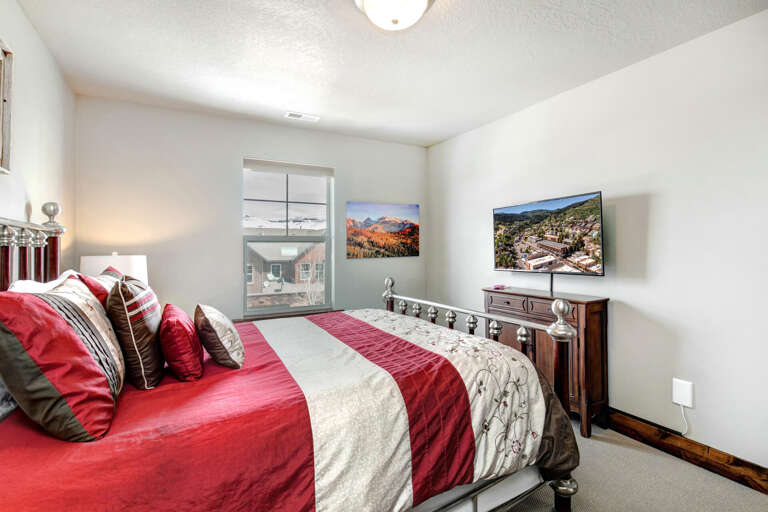 Relax in your serene bedroom with a plush bed dressed in vibrant linens and scenic mountain artwork adorning the walls.