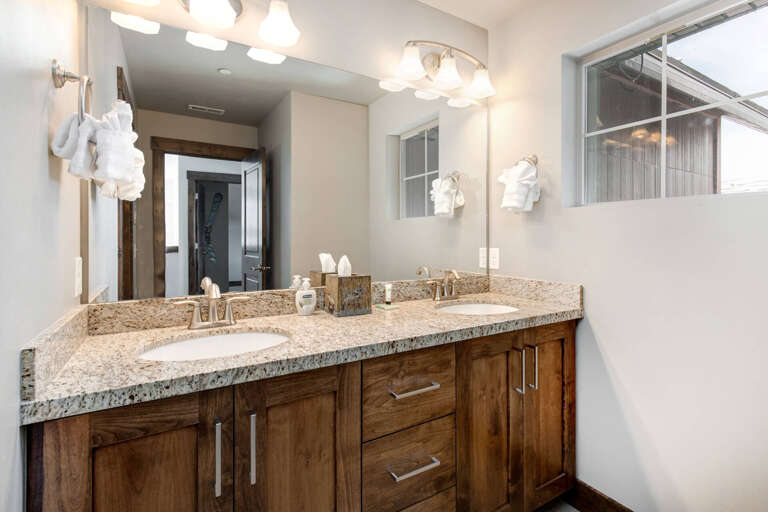 Your private bathroom features a spacious double vanity with warm wood cabinetry, granite countertops, and plenty of storage for all your essentials during your stay.