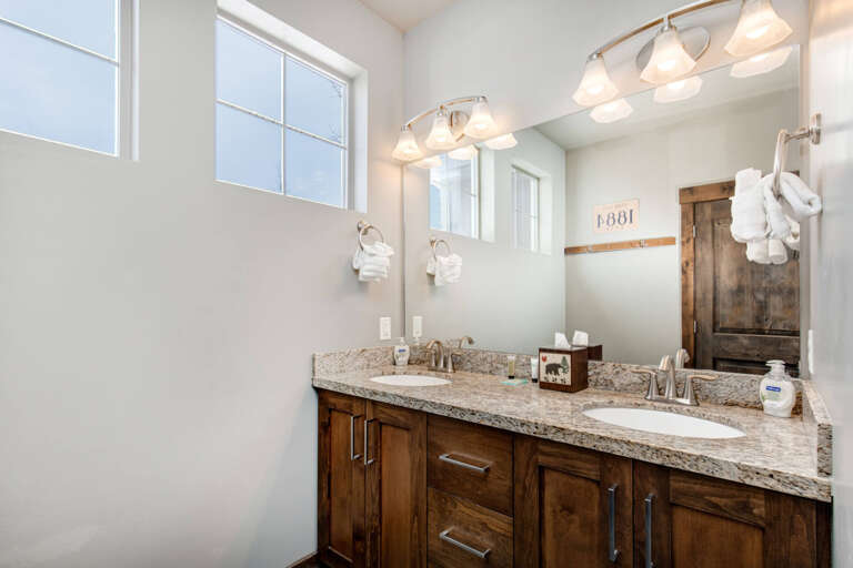 Unwind in your spacious bathroom with dual vanities, warm wood cabinetry, granite countertops, and soft lighting—perfectly designed for your morning and evening routines.