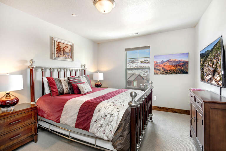 Your cozy retreat features a plush bed with elegant linens, nightstands with warm lighting, and mountain artwork to inspire your adventure ahead.