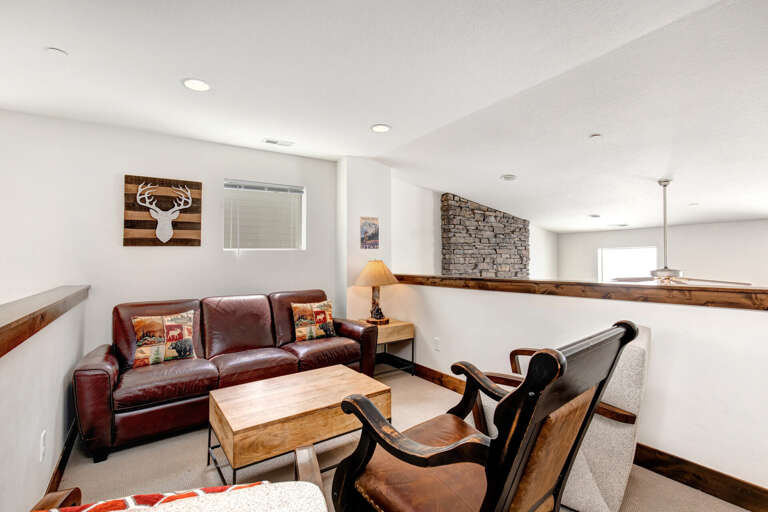 Sink into plush leather seating in your private loft lounge, where rustic charm meets modern comfort beneath soaring ceilings and a striking stone accent wall.