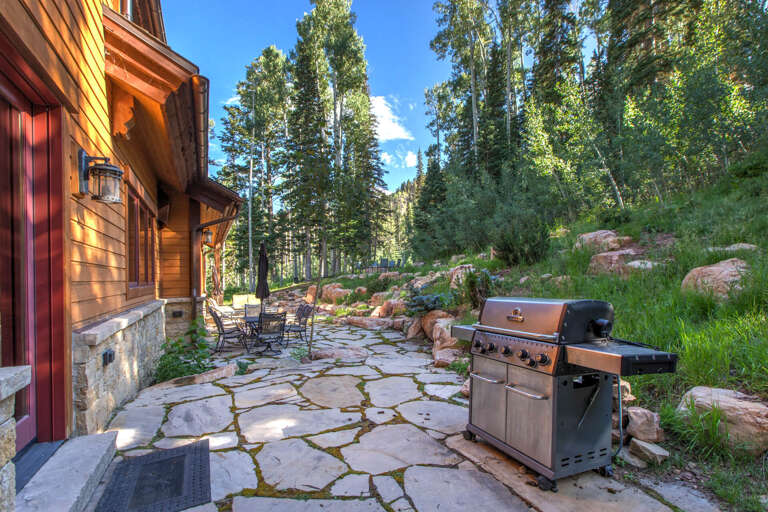 The stone patio is framed by towering aspens and natural rock landscaping. Fire up the grill, settle into a cozy chair, and let the mountain air embrace your outdoor dining experience.