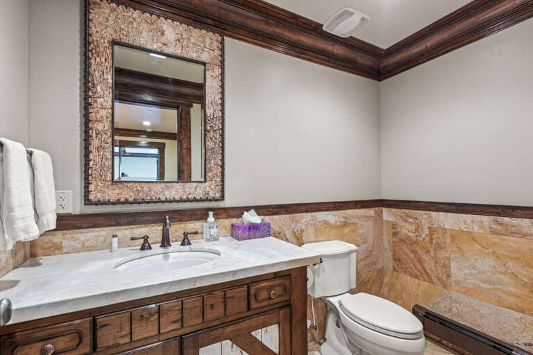 Your private bathroom features a beautiful seashell-framed mirror, elegant marble countertops, warm wood accents, and fresh towels awaiting your arrival.