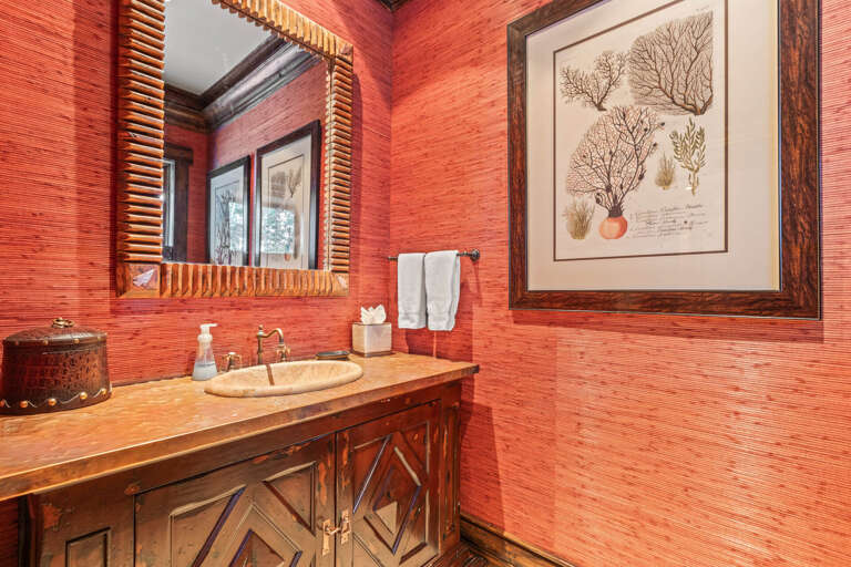 Vibrant coral-toned walls and warm wood accents create a uniquely inviting space where you can freshen up in style and comfort.