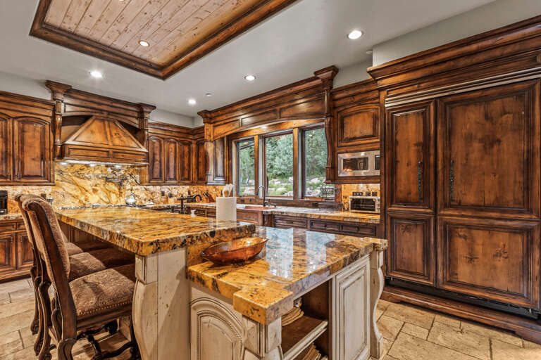 Step into your gourmet chef's paradise with gleaming granite countertops, rich custom cabinetry, and a stunning wood-beamed tray ceiling that elevates every culinary moment.