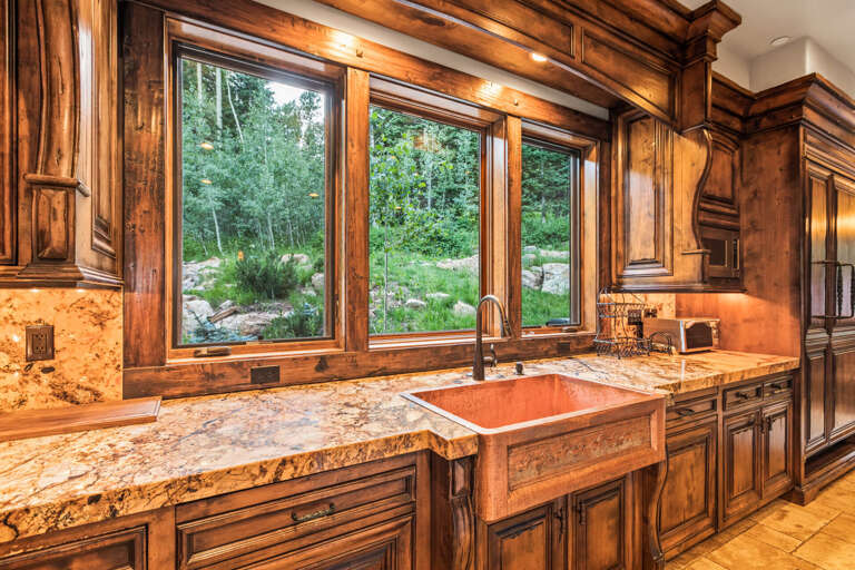 Prepare your favorite meals in this stunning kitchen featuring granite countertops, a copper farmhouse sink, and peaceful views of the surrounding aspen grove and natural landscape.