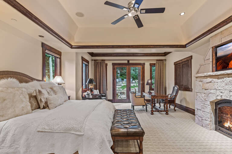 Luxurious bedroom suite with plush bedding, cozy fireplace, and elegant seating area opening to your private outdoor space—your perfect mountain retreat awaits.