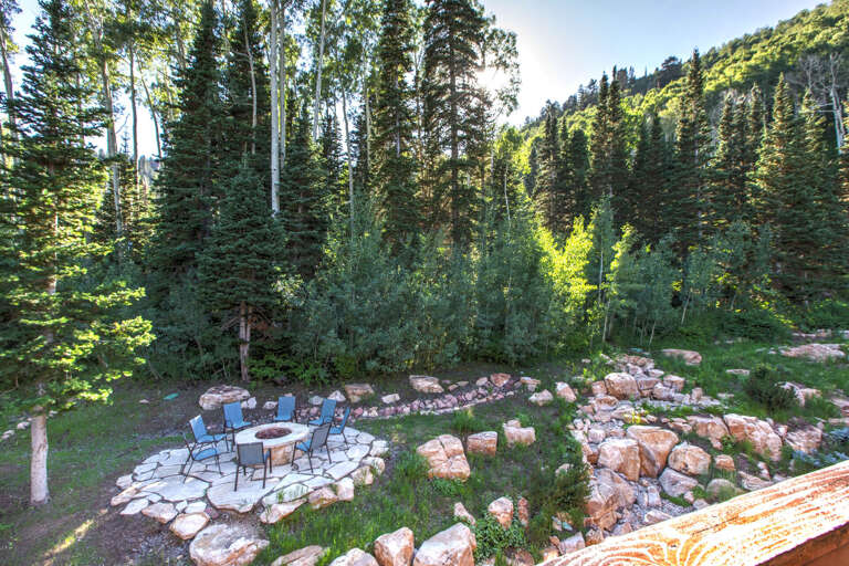 Nestled among towering evergreens and alpine terrain, this fire pit area offers a peaceful outdoor retreat surrounded by nature's beauty.