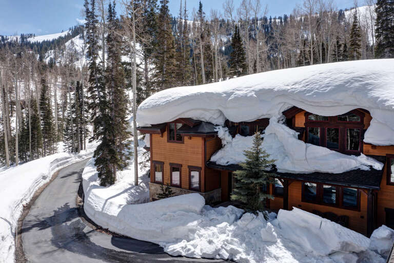 A snow-blanketed alpine retreat nestled among evergreens and aspens, offering ski-in access and breathtaking mountain views from this secluded woodland escape.