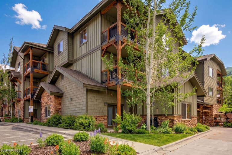 Contemporary mountain architecture featuring warm wood accents and multi-level balconies, nestled in a lush alpine setting. A welcoming summer retreat surrounded by nature.