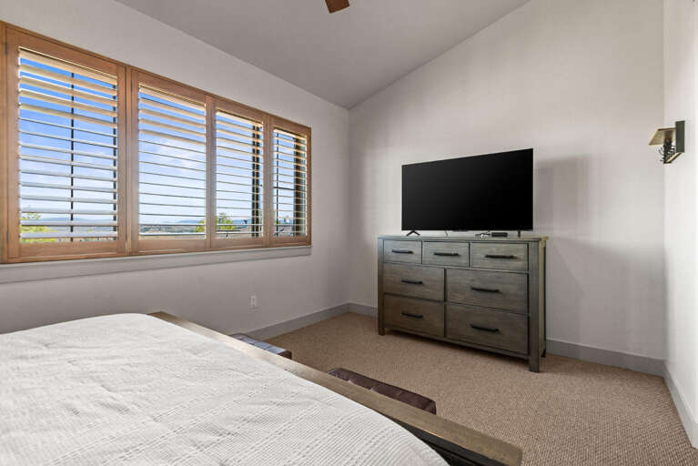 Step into your restful retreat featuring soft natural light and a calming ocean view through plantation shutters, perfect for unwinding after a day of adventure.