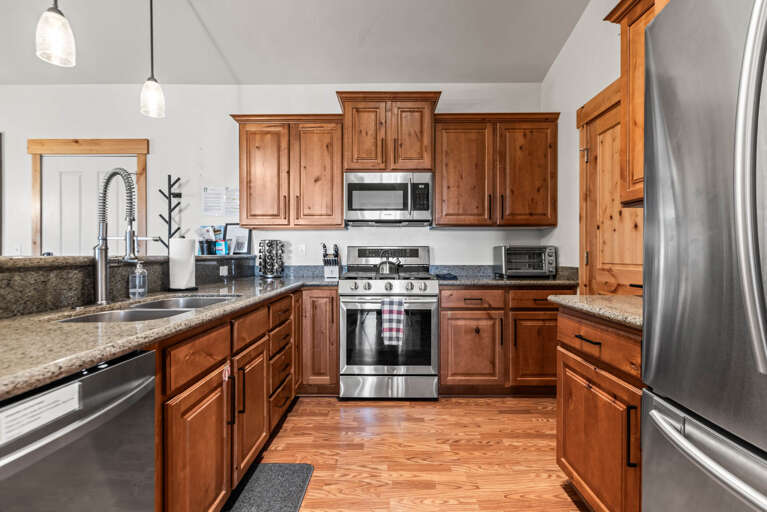 Your fully equipped kitchen features warm wood cabinetry, granite countertops, and stainless steel appliances—perfect for preparing home-cooked meals during your stay.