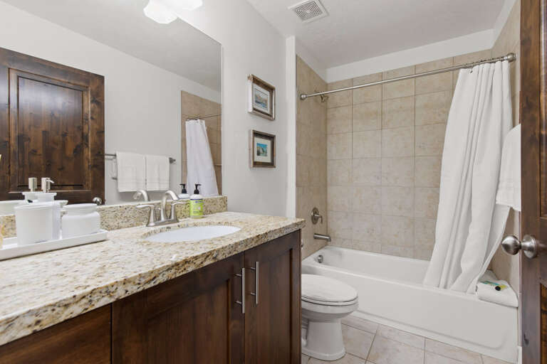 Your private bathroom features a spacious vanity with granite countertops, a full tub-shower combo, and warm wood accents that create a welcoming, home-away-from-home atmosphere.