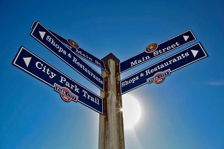 Directional signage marking Main Street and City Park Trail, guiding visitors to shops and restaurants in the historic town center.