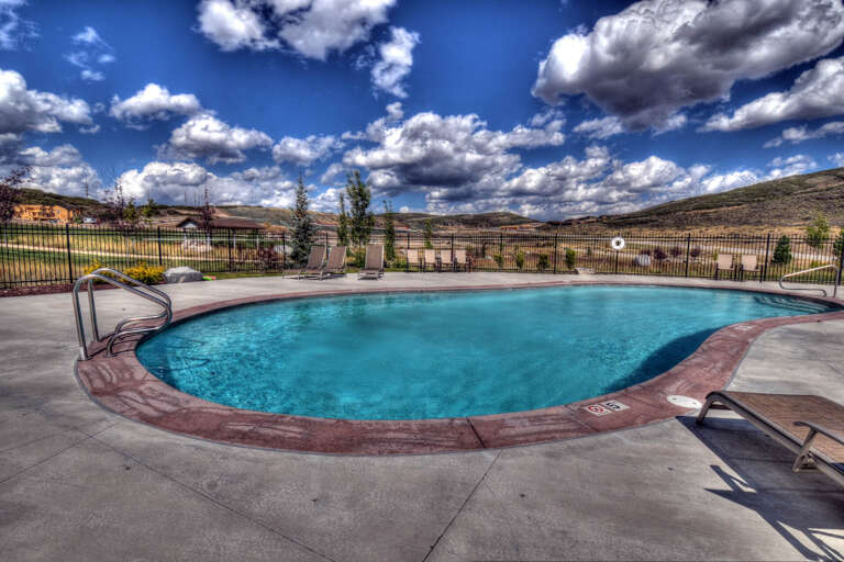 Outdoor pool surrounded by rolling hills and dramatic clouds, offering a peaceful desert-landscape setting for relaxation.