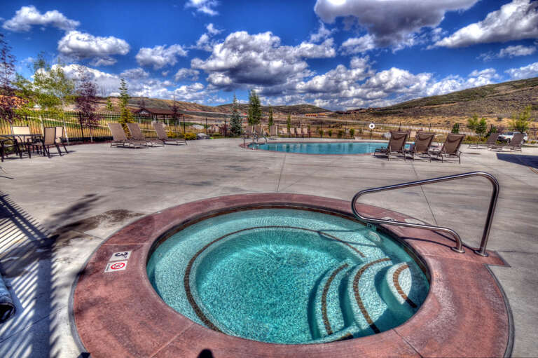 Soak in the sparkling hot tub surrounded by stunning mountain views, then relax by the pool under a brilliant sky—your perfect retreat awaits.