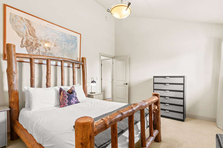 Sink into crisp white linens on this handcrafted log bed. A Montana map overhead and bright natural light create a peaceful mountain retreat perfect for restful nights.