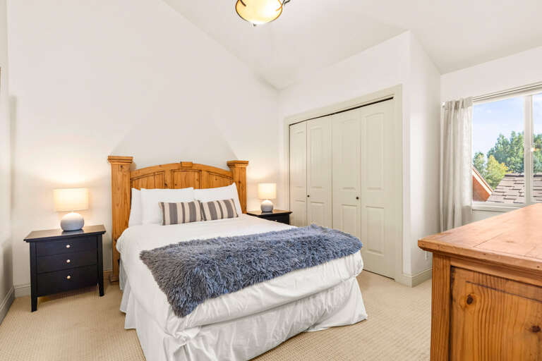Relax in your private bedroom featuring a cozy bed with plush bedding, warm wood accents, and natural light streaming through the window—your perfect retreat after a day of adventure.