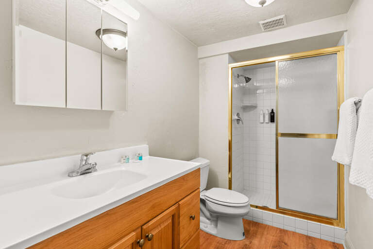Step into your freshly refreshed bathroom with white subway tile shower, warm wood cabinetry, and polished brass accents—a clean, classic space to start or end your day.